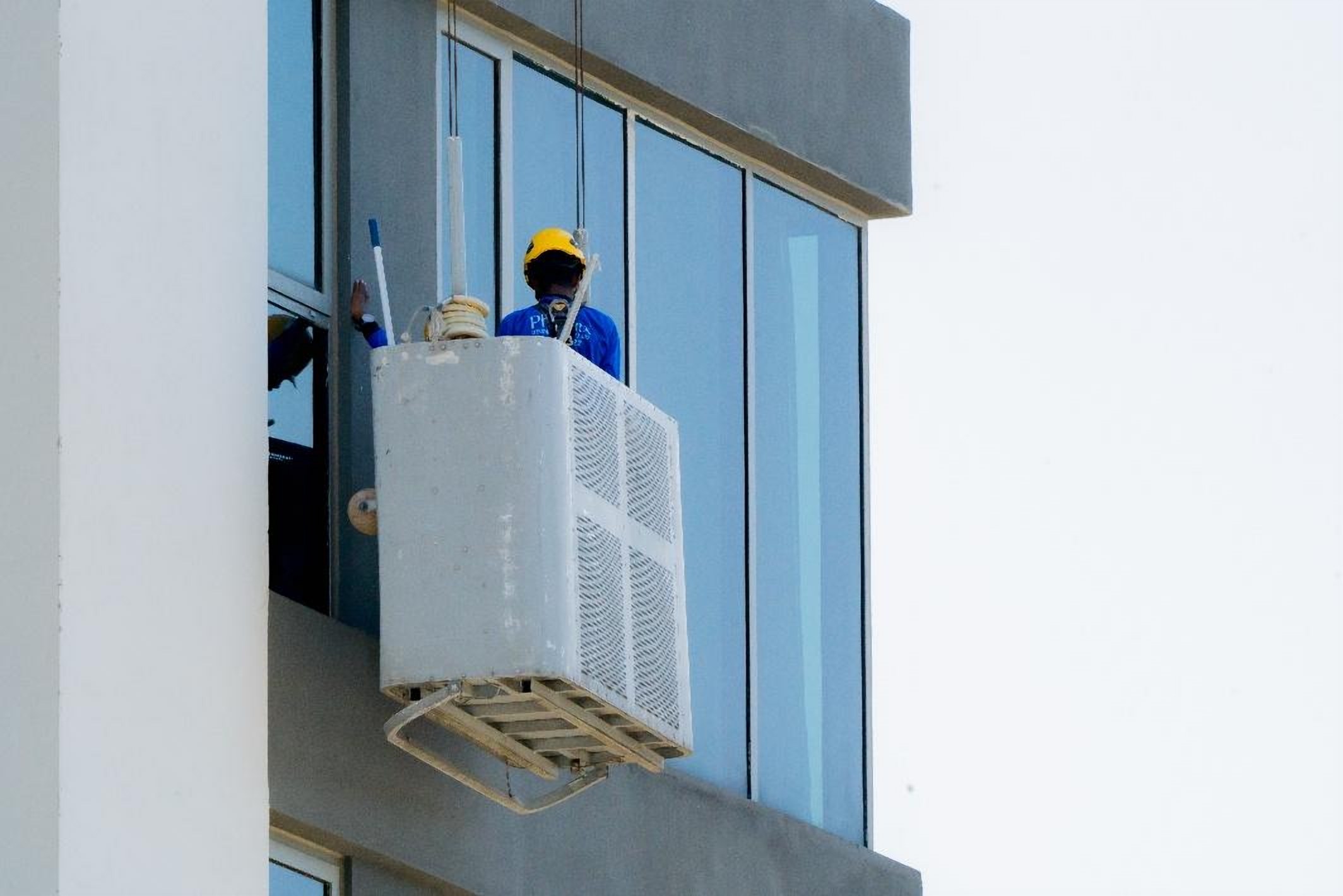 Technician working from a gondola on a glass facade